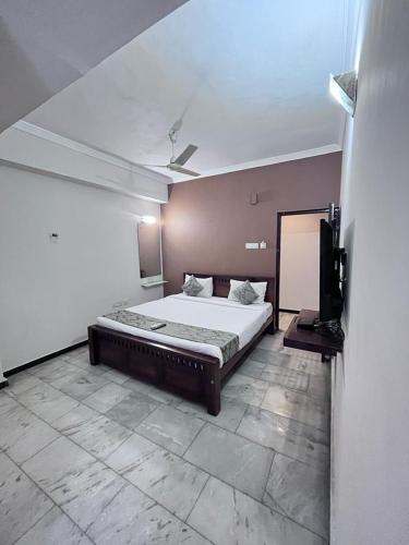 a bedroom with a bed and a flat screen tv at Le Grace Annasalai in Chennai