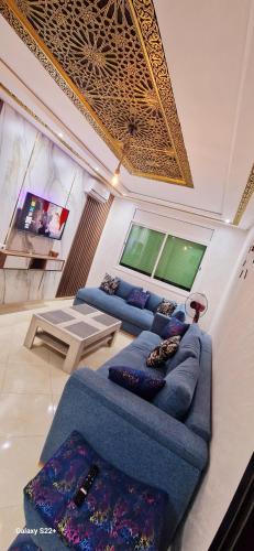 uma sala de estar com dois sofás azuis e uma televisão em Suite Home Prestige em Kenitra