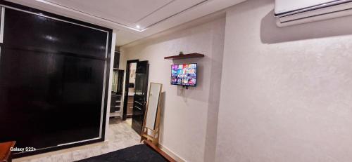ein Wohnzimmer mit einem großen schwarzen TV an der Wand in der Unterkunft Suite Home Prestige in Kenitra
