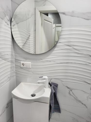 a bathroom with a white sink and a mirror at Apartamentai in Garliava