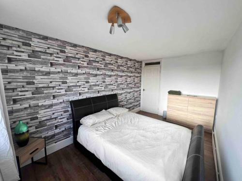 Un dormitorio con una pared de ladrillo y una cama en Lovely Furnished 1 Bedroom Flat in historic St Albans. Sleeps 4, en Saint Albans