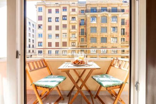 una mesa y sillas en un balcón con ventana en Lapurdi Zurriola Beach, en San Sebastián