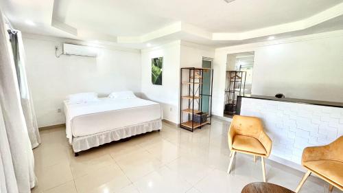 a white bedroom with a bed and a chair at Terras Verdes Residence in Fernando de Noronha