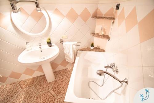a bathroom with a sink and a mirror and a tub at Manno 81 - Charming historic apartment in Cagliari