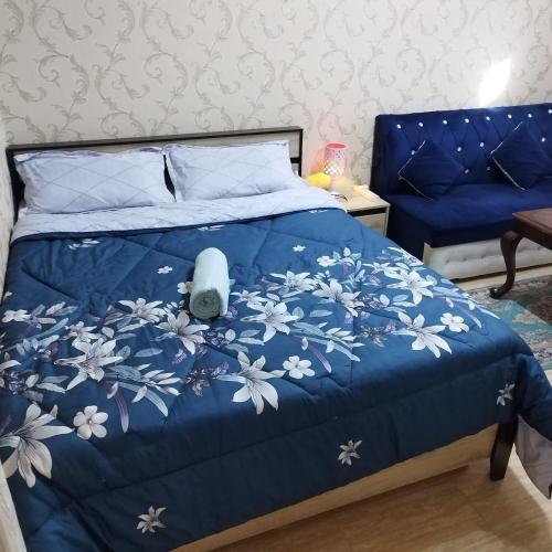 a blue bed with a blue comforter with white flowers at العين الهيلي مصباح بيت 12 in Al Ain