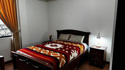 um quarto com uma cama e uma mesa com um candeeiro em Wasi Golde oro em Otavalo