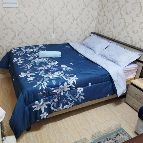 a bed with a blue comforter with a blue and white bedspread at العين الهيلي مصباح بيت 12 in Al Ain