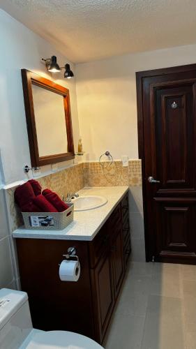 uma casa de banho com um lavatório, um espelho e um WC. em Wasi Golde oro em Otavalo