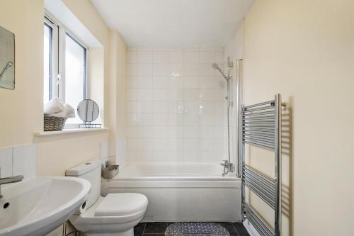 a white bathroom with a tub and a toilet and a sink at Lt Properties Unique Bungalow style Spacious one bedroom Apartment in Luton Town centre super size round bed Netflix in Luton