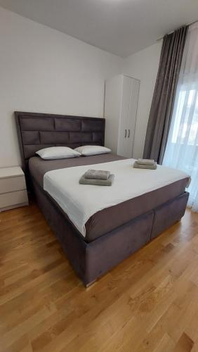 ein großes Bett in einem Schlafzimmer mit Holzboden in der Unterkunft Studio Apartment Smile Mostar in Mostar