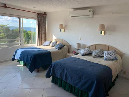 1 dormitorio con 2 camas y ventana grande en Suites Brisas Cancun, en Cancún