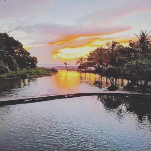 a pool of water with a sunset in the background at DOÑA CORNELIA in Los Patos