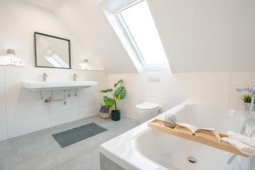Sleeping Home - Red House في بيليفيلد: حمام ابيض مع حوض استحمام ومغسلة