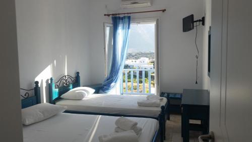 two beds in a room with a window at Sofia's Studios in Artemonas