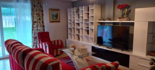 a living room with a television and red chairs at Casa Rotella in Puente San Miguel