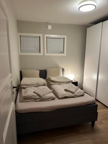 Cama en habitación pequeña con 2 ventanas en Fin leilighet, sentralt og sjønært,med parkering en Arendal