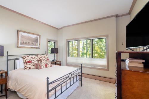 a bedroom with a bed and a flat screen tv at Ski in Ski out Village Creek condo in the Mountain Village Core in Telluride