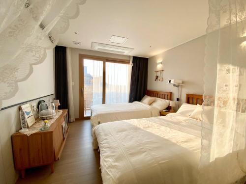 a hotel room with two beds and a window at Morning Madrid in Jeju