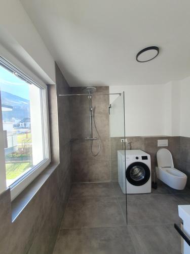 a bathroom with a shower and a toilet and a window at little alpenapart in Volders