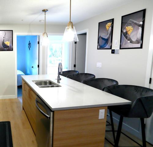 a kitchen with a sink and some black chairs at Mountain Retreat: Brand New 2BR Condo in Canmore