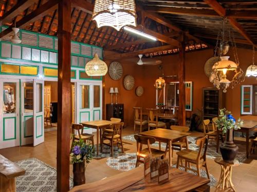 Omah Mbah Manten في Tuntang: غرفة طعام بها طاولات وكراسي وثريات