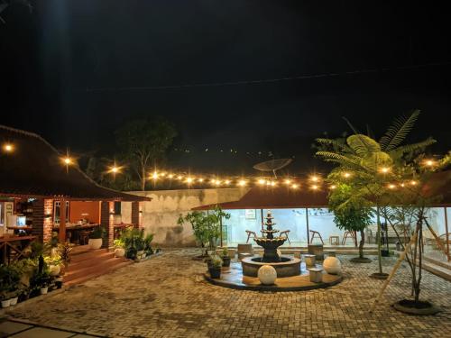 a courtyard at night with a fountain and lights at Omah Mbah Manten in Tuntang