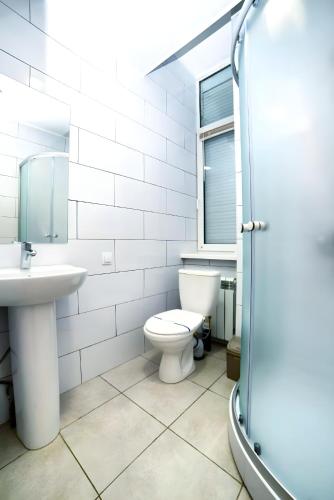 a white bathroom with a toilet and a sink at Atlas Hotel in Poltava