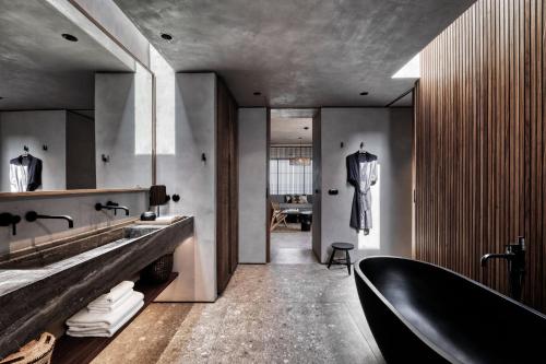 a bathroom with a black tub and a sink at Domes Zeen Chania, a Luxury Collection Resort, Crete in Kato Daratso