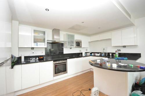 a kitchen with white cabinets and a black counter top at EXCEL STUNNING DUPLEX PENTHOUSE in London