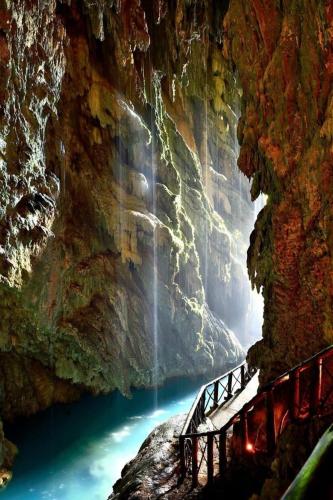 a bridge over a river in a cave with a waterfall at Apartamentos Nenufar in Alhama de Aragón