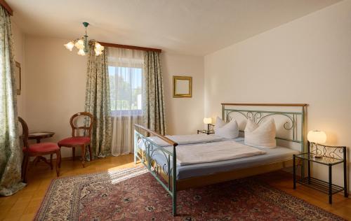 a bedroom with a bed and a chair and a window at Hotel Garni Demmel in Bruckmühl