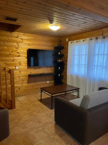 uma sala de estar com uma televisão, um sofá e uma mesa em Chalé do Sossego Serra da Estrela em Cortes do Meio