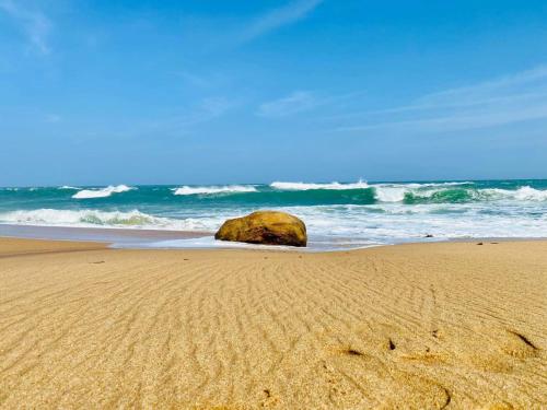 una playa con una roca en la arena y el océano en Yala Beach Resort, en Kirinda