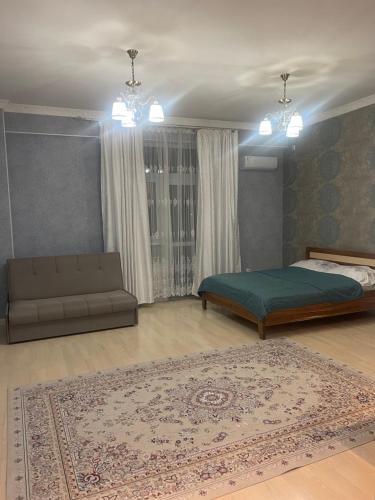 1 dormitorio con cama, sofá y alfombra en Green Plaza 10-11, en Aktau