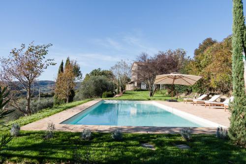 a swimming pool in a yard with an umbrella at CASALE ORTALI by Miani Group in Pesciano