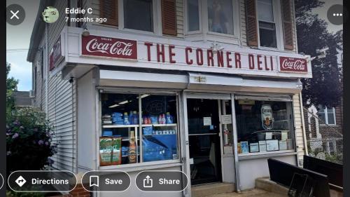 a store with a sign that reads the corner deli at Cozy Apartments Woodside near Manhattan in Queens