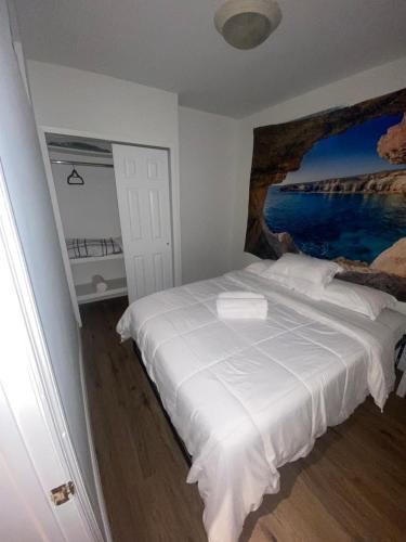 a bedroom with a white bed with a painting on the wall at Cozy Apartments Woodside near Manhattan in Queens