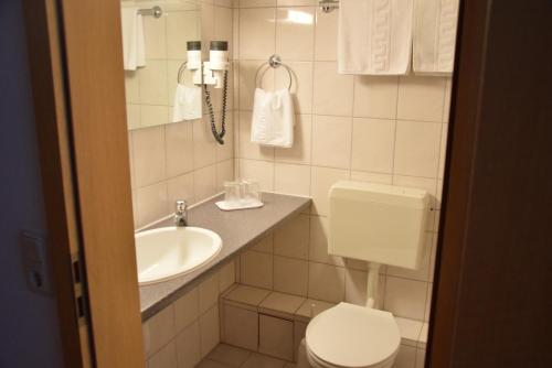 ein Bad mit einem WC und einem Waschbecken in der Unterkunft Niebuhrs Hotel in Friedrichsdorf
