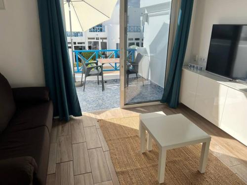 ein Wohnzimmer mit einer Couch und einem Tisch und einem Fernseher in der Unterkunft 26 Puerto del Carmen Palm tree in Puerto del Carmen