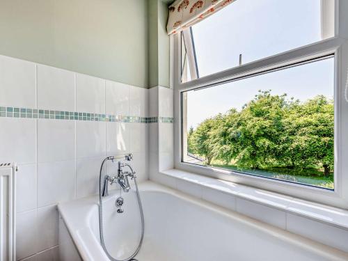 a bathroom with a bath tub and a window at 3 Bed in Brechfa 92116 in Rhyd-cymmerau