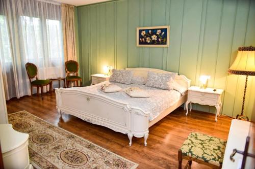 a bedroom with a white bed and two chairs at Former Ceausescu's Vila Crizantema in Băile Govora