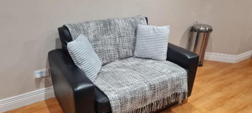 uma cadeira preta com um cobertor e almofadas em 2 bed cosy apartment in heart of Mullingar. em Mullingar