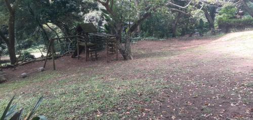 a stack of chairs sitting under a tree at Timber Ally Cabin in Umtentweni