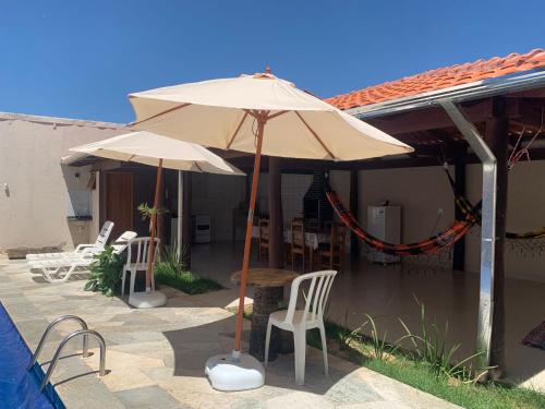 un patio con 2 sombrillas, una mesa y sillas en Casa 2M no Centro de Piri, en Pirenópolis