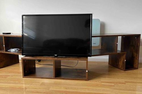 TV de pantalla plana grande con soporte de madera en Charming 2Bedroom Retreat in Great Barr/Hamsted en Birmingham