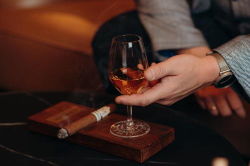 a person holding a glass of wine and a cigar at The Ritz-Carlton, Berlin in Berlin