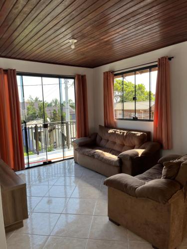 Una sala de estar con dos sofás y una gran ventana. en Casa no centro de Garopaba, en Garopaba