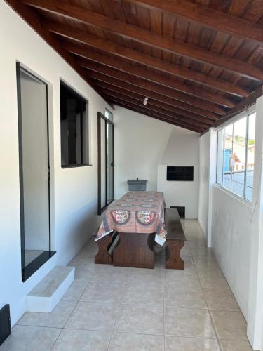 Habitación con mesa y algunas ventanas. en Casa no centro de Garopaba, en Garopaba