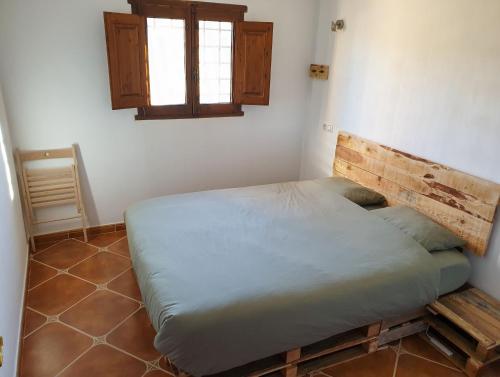 a bedroom with a bed with a wooden headboard and a window at Casa La Sorpresa in La Ermita del Piar