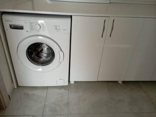 eine weiße Waschmaschine in einer Küche mit weißen Schränken in der Unterkunft Stadt mitte in Antalya